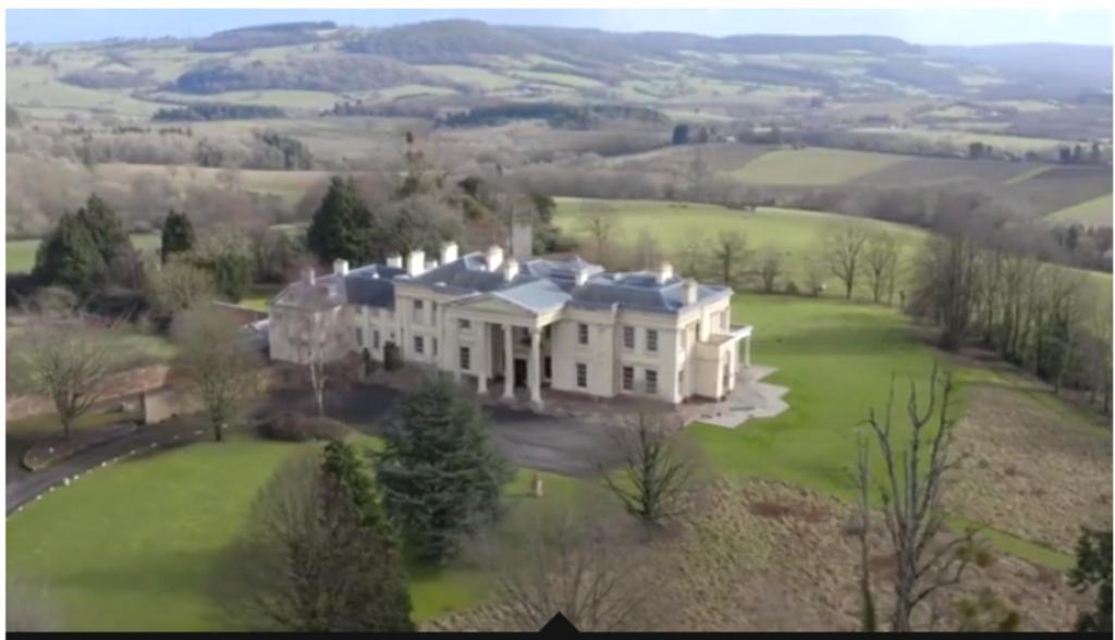 an aerial view of a large white house on a green field at Hilston Park in Monmouth