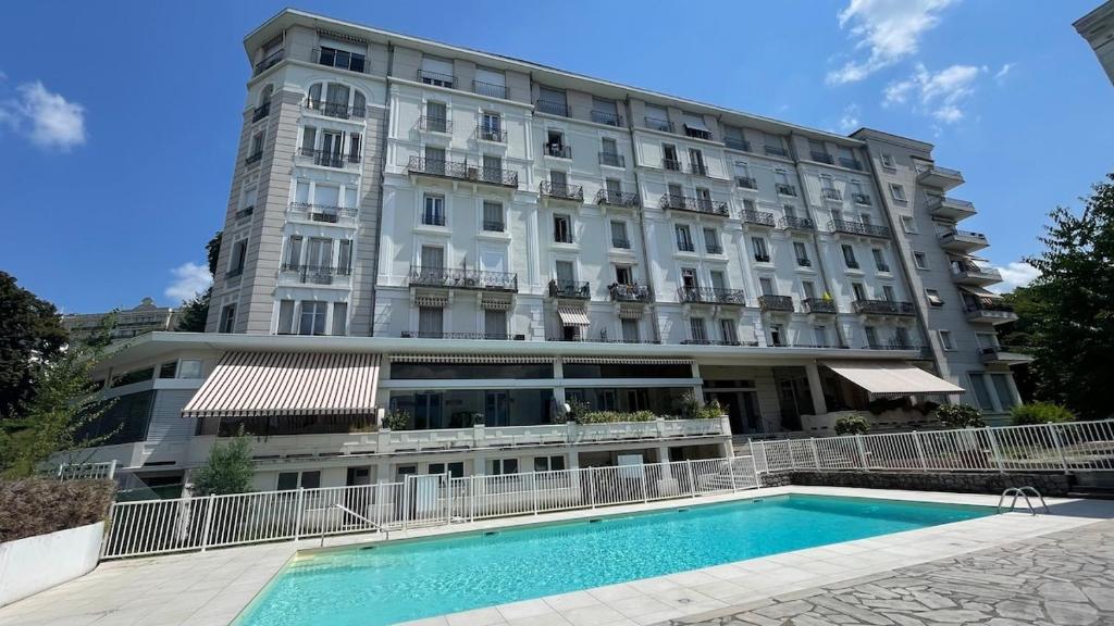 un grand bâtiment avec une piscine devant dans l'établissement Studio calme, piscine - Proche thermes et centre, à Aix-les-Bains