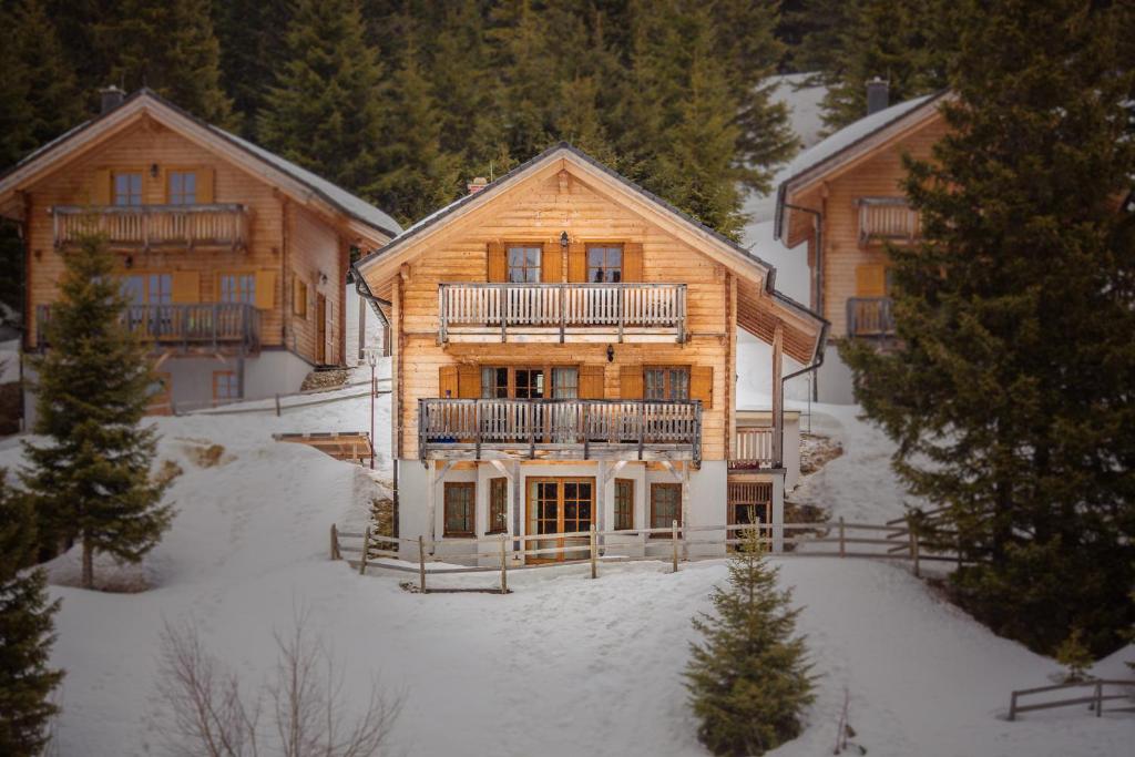 a large wooden house with snow on the ground at Feriendorf Koralpe Chalet Edelweiss in St. Gertraud