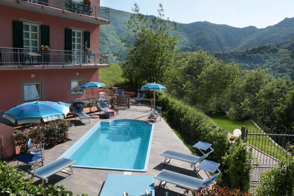 a hotel with a swimming pool with chairs and umbrellas at Hotel Ca' De Berna in Balestrino