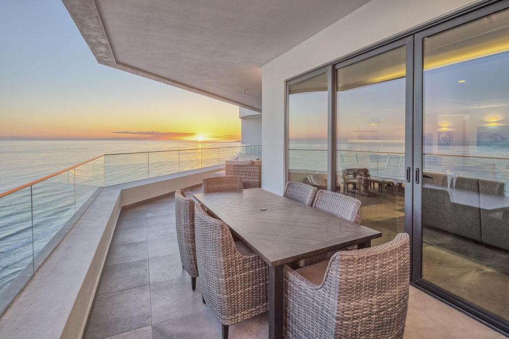 a balcony with a table and chairs and the ocean at LUXURY NEW OCEANFRONT CONDO 5BR Sleeps 12 in Puerto Peñasco