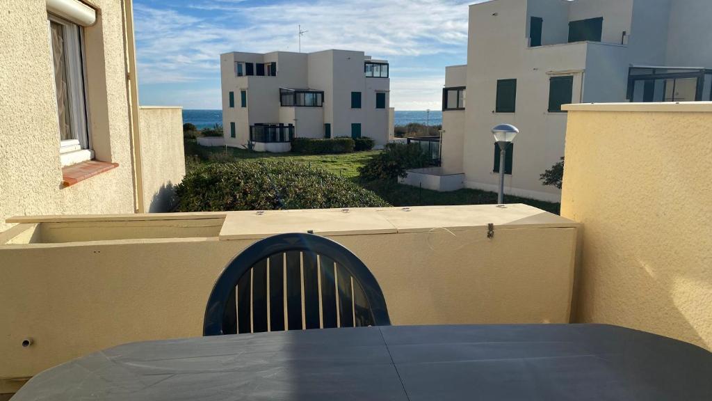 a table on a balcony with a view of some buildings at Appartement Grand Large - 3 pièces - 5 couchages in Le Barcarès
