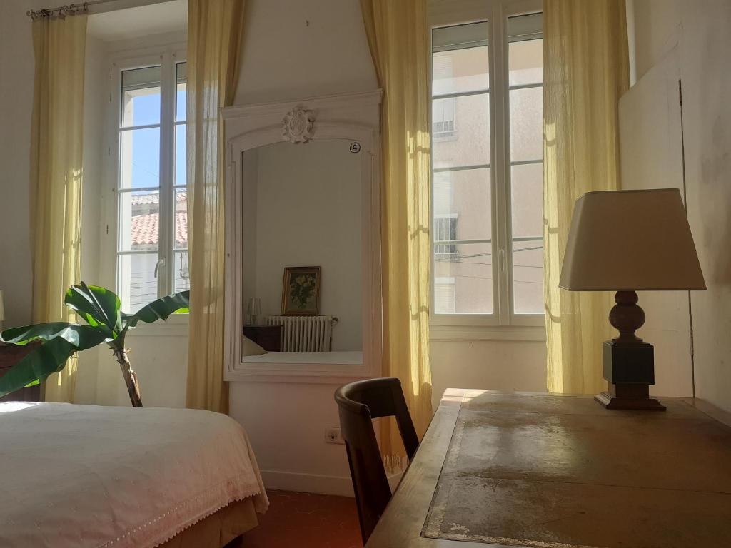 une chambre avec un lit, une table et un miroir dans l'établissement Chambre avec parties communes ambiance méditerranée, à Port-la-Nouvelle