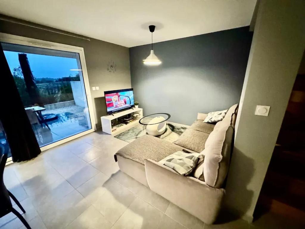 un salon avec un canapé et une télévision dans l'établissement Maison lumineuse à Restinclières avec jardin et terrasse, à Restinclières