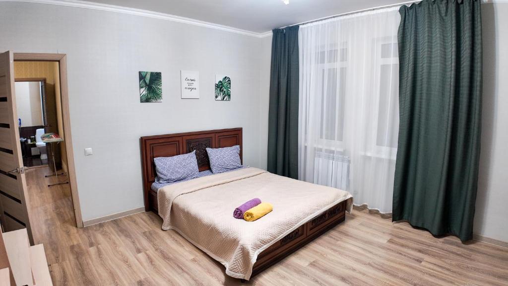 a bedroom with a bed with a yellow pillow on it at Apartment Promenade EXPO in Astana