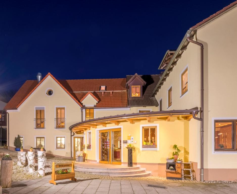a large white house with a lit up facade at night at Landhotel Zum Goldenen Kreuz in Moosbach