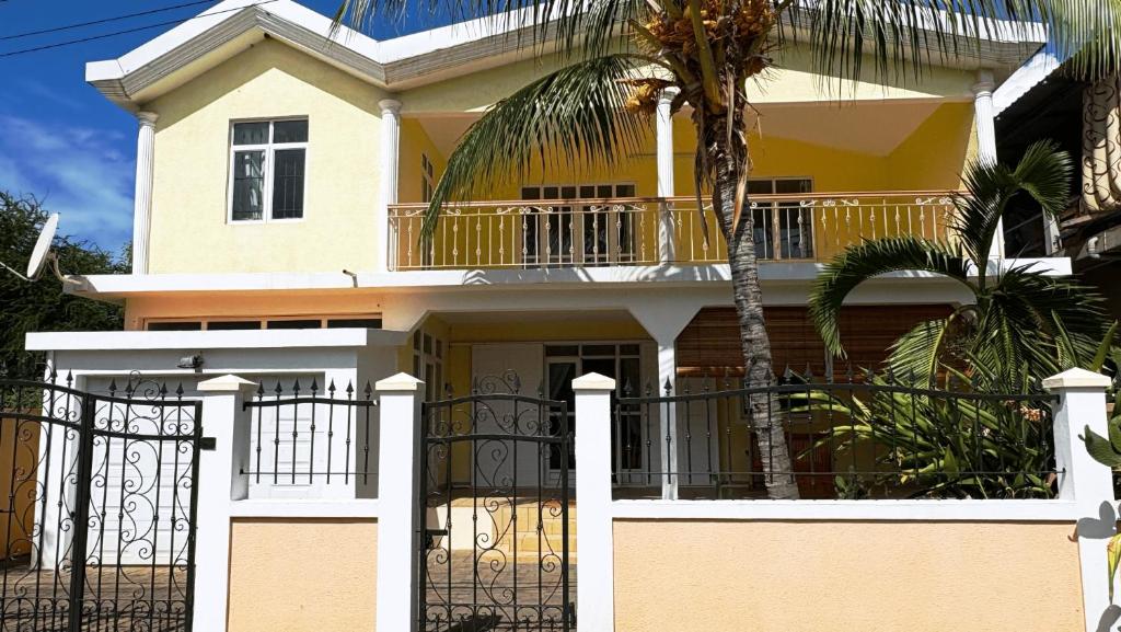 a yellow house with a gate and a palm tree at Villa calme 5 chambres, proche plage et terrasses in Port Louis
