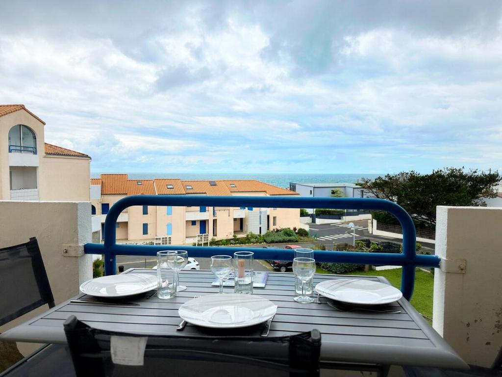 une table en bois avec des assiettes et des verres sur un balcon dans l'établissement Cozy nest sea view, à Les Sables-dʼOlonne