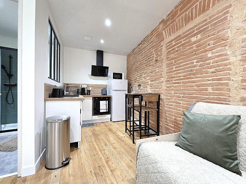 un salon avec un canapé et un mur de briques dans l'établissement Le Briand - Studio pour 2 personnes - Climatisation - Fibre internet - 5 min à pied de la gare et du centre-ville - Places de stationnements gratuites sur toute l'avenue, à Montauban