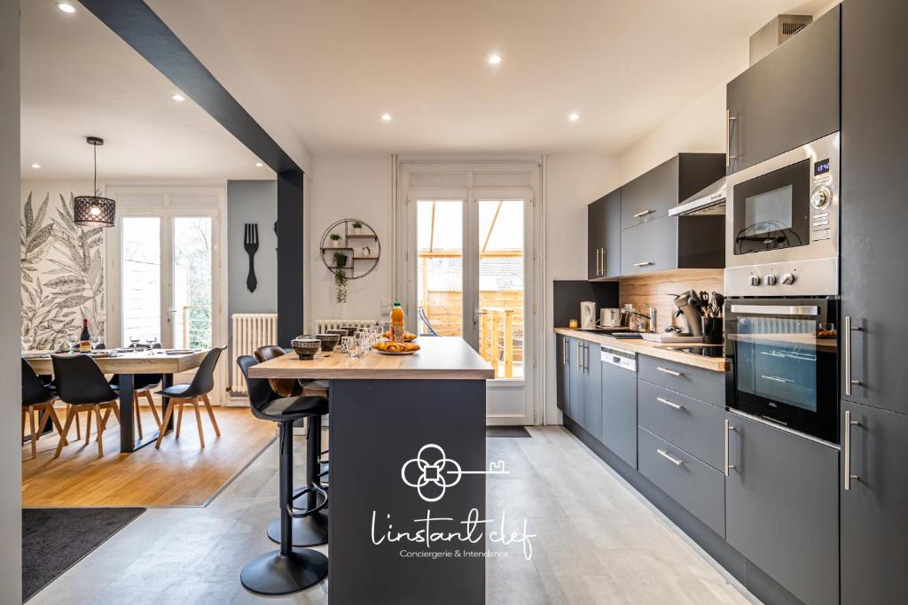 a kitchen with gray cabinets and a dining room at Maison d exception au Mans Garage XXL et Terrasse in Le Mans