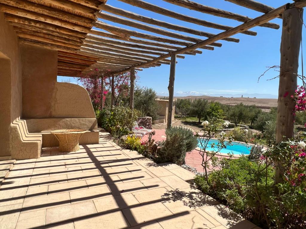 a patio with a pergola and a swimming pool at Les Jardins de la Santé in Tamazouzte