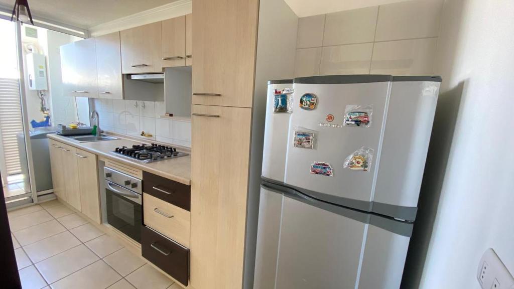 a kitchen with a white refrigerator with magnets on it at departamentos La Serena in La Serena
