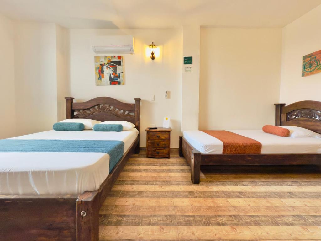 due letti in una stanza con pavimenti in legno di Santiago DC Hotel a Cali