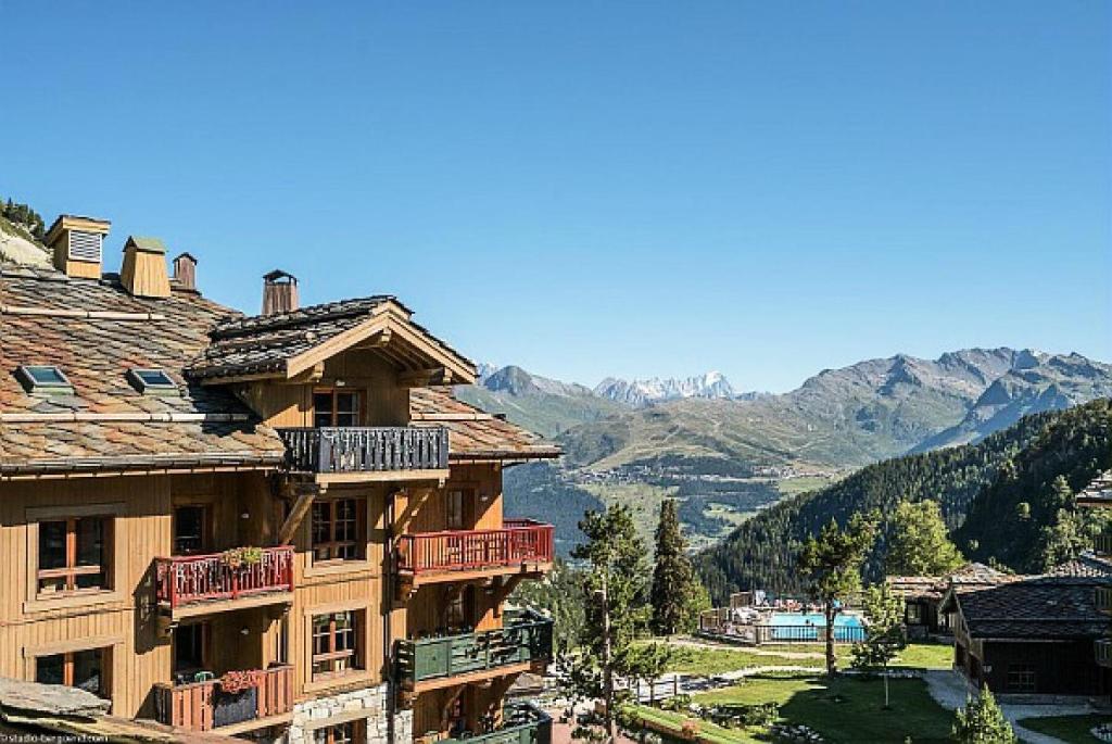un grand bâtiment avec des balcons et des montagnes en arrière-plan dans l'établissement Résidence Les Arcs 1950 Le Village - maeva Home - Appartement 4 pièces 8 personnes - Exclusive MAE-4121, à Arc 1950