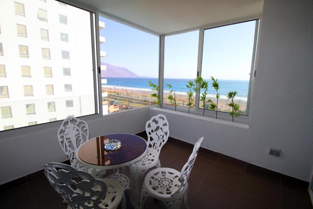 um quarto com uma mesa e cadeiras e vista para o oceano em Edificio Mirador em Iquique