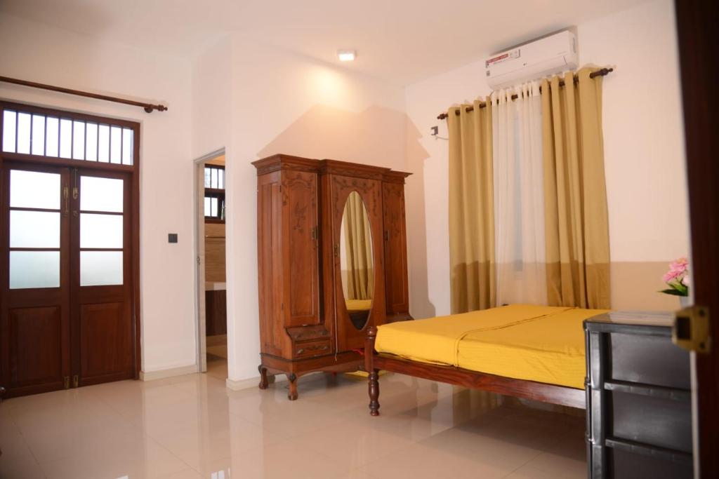 a bedroom with a bed and a dresser and a mirror at Villa KN in Ambalangoda