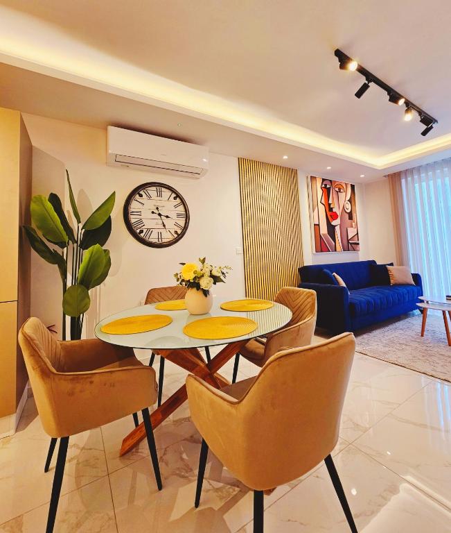a living room with a table and chairs and a clock at Delmar Coastal Retreat in St. Paul's Bay