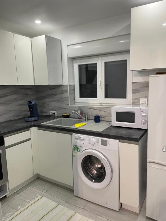 une cuisine avec un lave-linge et un micro-ondes dans l'établissement Maison de campagne, à Fabrègues