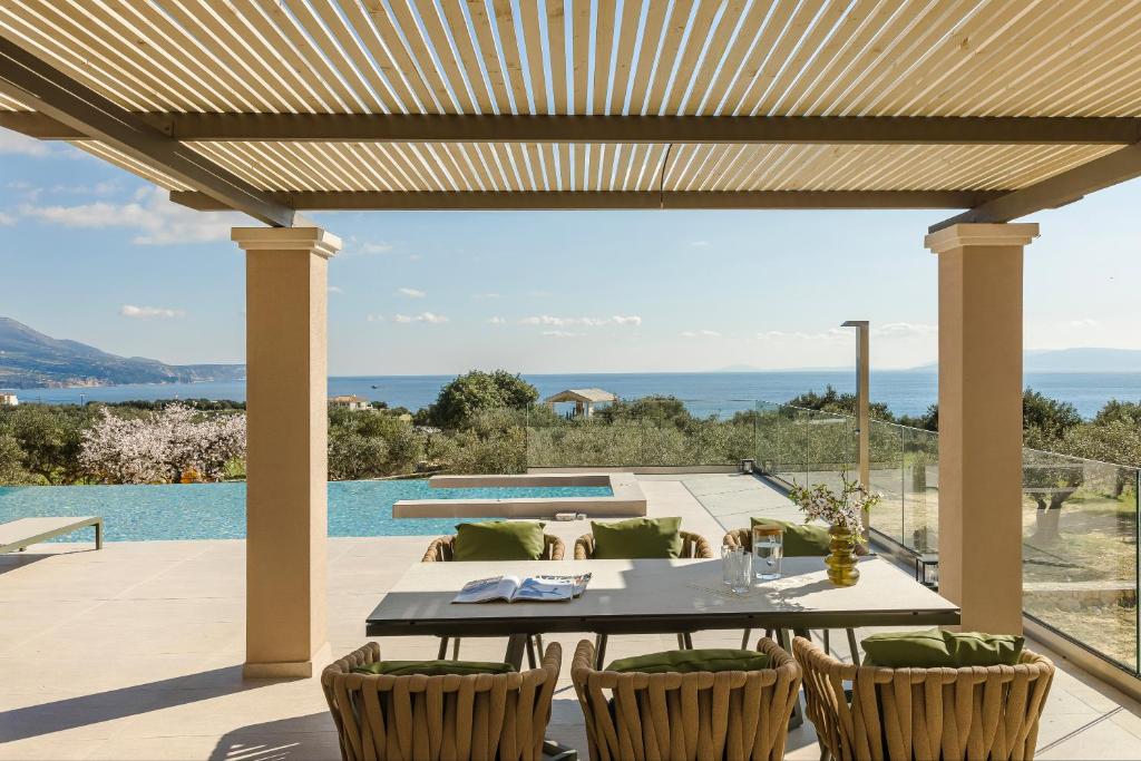 un patio con tavolo e sedie e una piscina di Villa Oro di Agathera Kefaloniaprivatevillas ad Argostoli