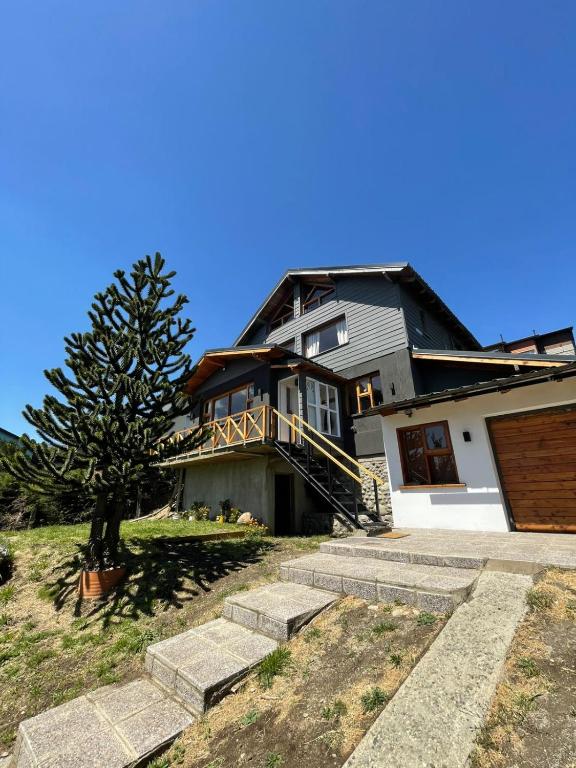 a house with a tree and stairs in front of it at Increíble vista al Lago, Casa vacacional "Las Victorias Sur" in San Carlos de Bariloche