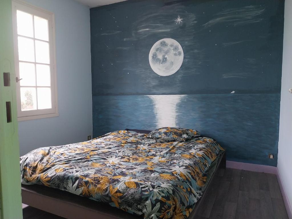 - une chambre avec un lit avec la lune sur le mur dans l'établissement jolie maison charentaise, à Marennes
