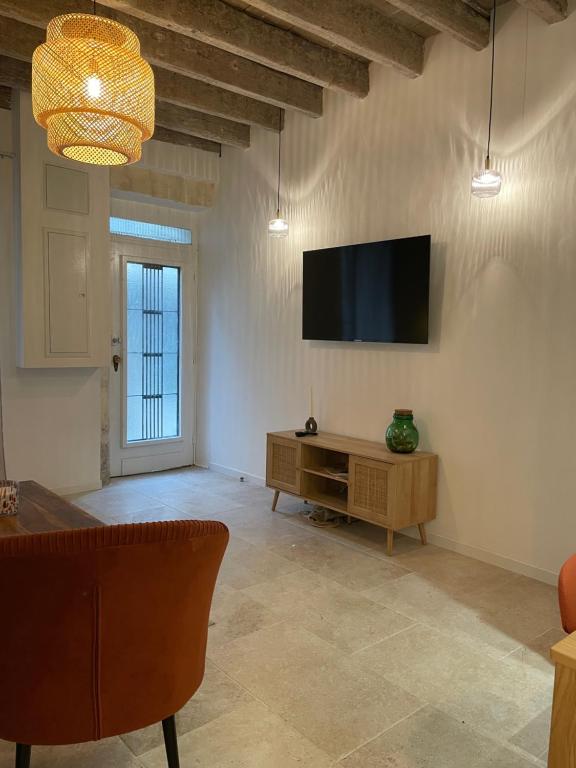 Una sala de estar con un televisor de pantalla plana en la pared. en Jolie maison en centre ville avec climatisation grand lit double, en Arles