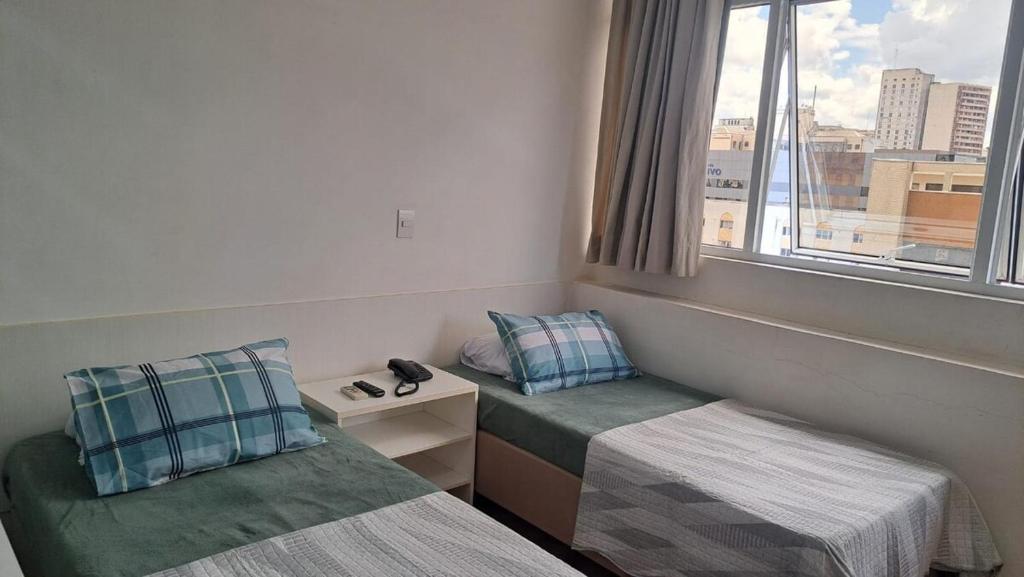 een kamer met twee bedden en een raam bij Flat Centro de Curitiba Rua 24 horas in Curitiba