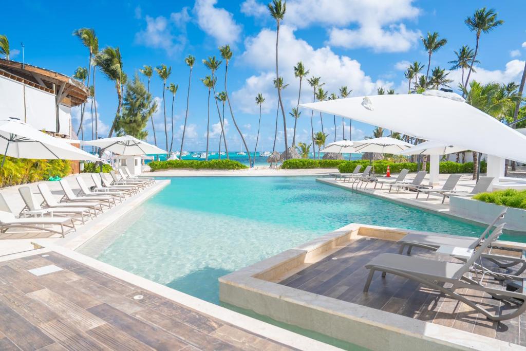 Xeliter Playa Coral, Bavaro في بونتا كانا: حمام سباحة في منتجع مع كراسي ومظلات