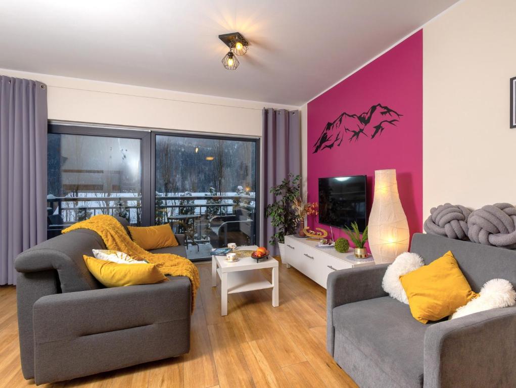 un soggiorno con 2 divani e una parete rosa di Beskid Apartment 6 z widokiem na góry, Sauna, Jacuzzi a Szczyrk