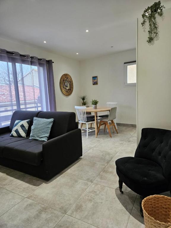 a living room with a black couch and a table at 200m de la plage en centre ville au calme in Le Grau-du-Roi