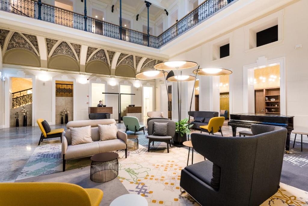 a large lobby with chairs and a piano at Hotel Moments Budapest in Budapest
