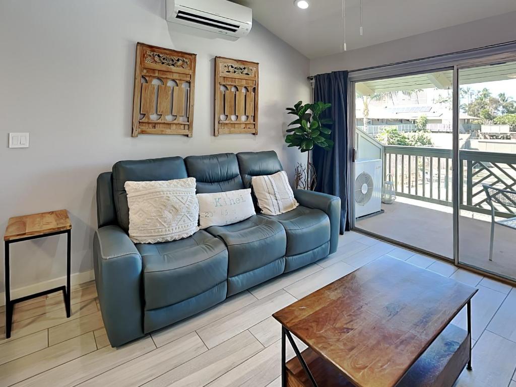 a living room with a blue couch and a table at Kihei Bay Surf 227 in Kihei
