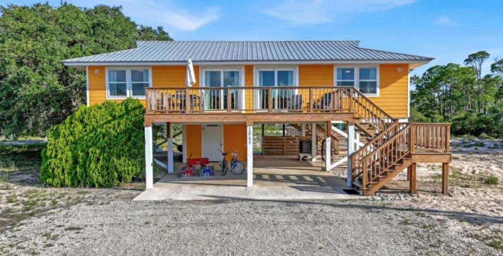 a yellow house with a deck on the beach at The Honey Hole St George Island Pet Friendly-Heated Private pool West Gulf beaches in St. George Island