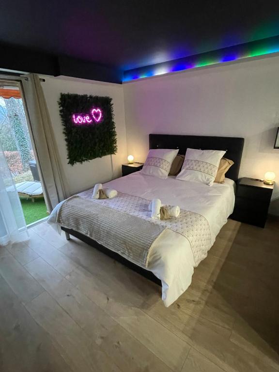 - une chambre avec un grand lit et un panneau de néon sur le mur dans l'établissement Love and bubbles, à Bœrsch