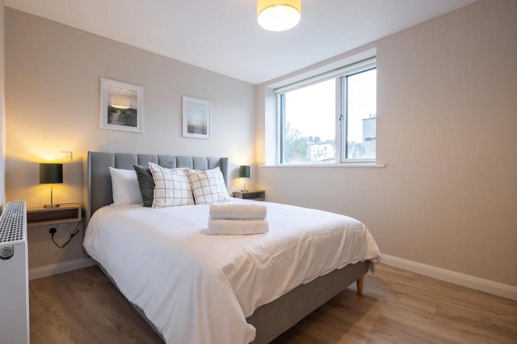 a bedroom with a large white bed with a window at 3rd Floor Stylish 2-Bed Apartment in Drogheda
