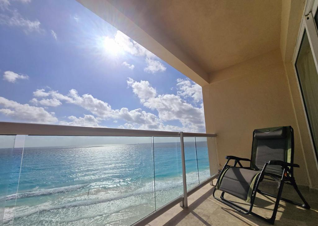una sedia su un balcone con vista sull'oceano di Cancun Beach & Nightlife Paradise SALVIA CONDOMINIUMS a Cancún