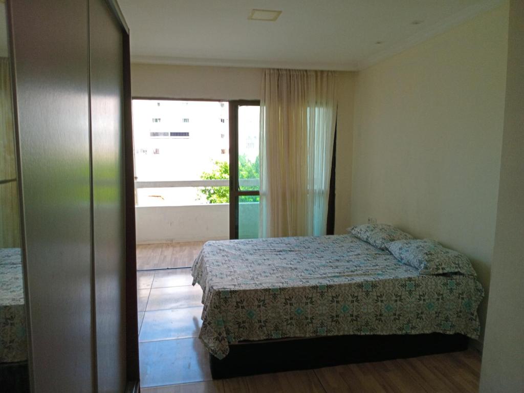una camera da letto con un letto e una grande finestra di Casinha Duplex na Avenida Centenário com varanda, Ar e Wi-Fi a Salvador