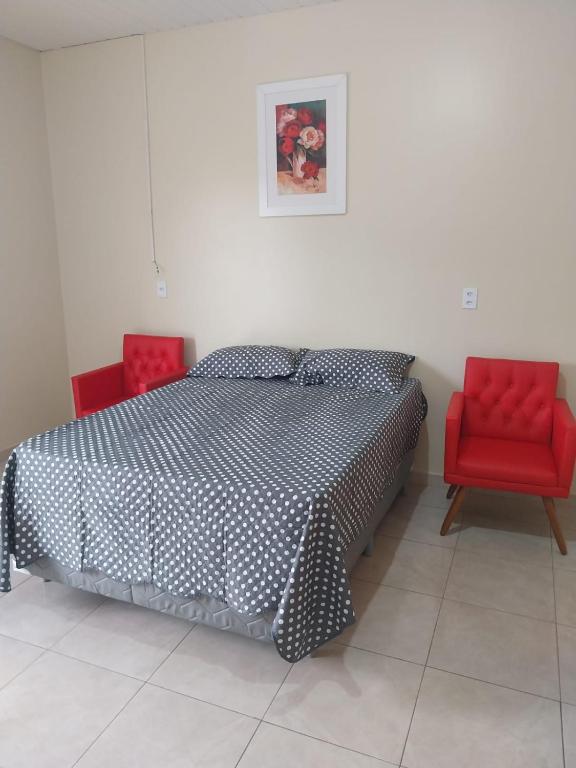 a bedroom with a bed and two red chairs at APT Raphis C in Santarém