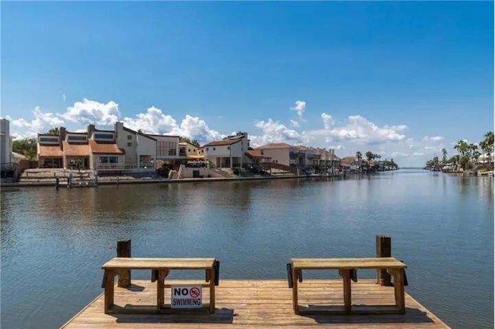two benches sitting on a dock next to a body of water at 3 bedroom 3 bath Condo in Corpus Christi