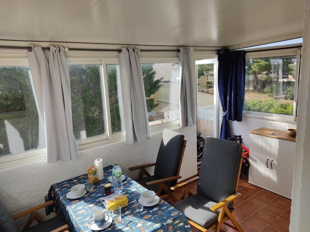 une salle à manger avec une table, des chaises et des fenêtres dans l'établissement Gruissan: 4 Pers, Clim, Parking, Proche Centre - FR-1-796-81, à Gruissan
