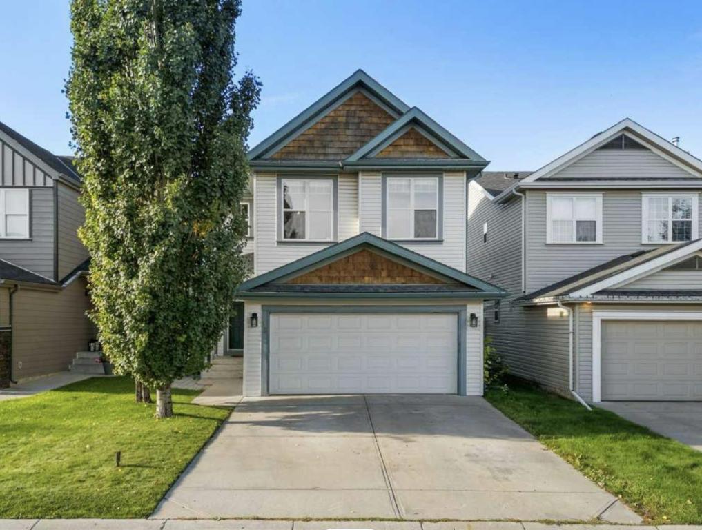 カルガリーにあるCozy Comfort Rooms in SE Calgary, Canadaの庭に二つのガレージドアがある家