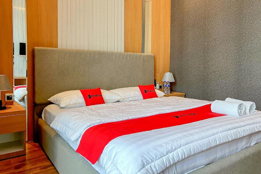 a large bed with red and white pillows on it at RedDoorz Premium at Hotel Riyadi Syariah in Gunungcupu