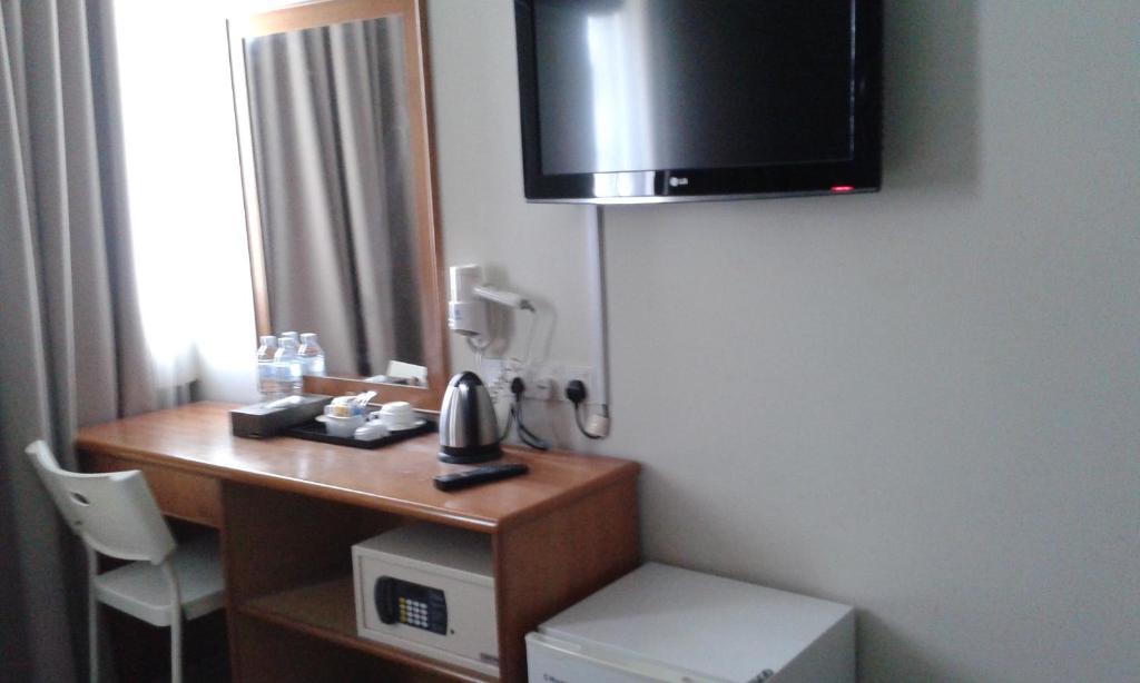 um quarto com uma secretária, um telefone e uma televisão em De Spring Hotel em Kuantan