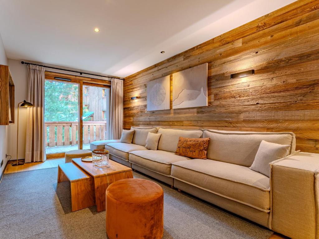 a living room with a couch and a wooden wall at Appartement 3 chambres à Méribel, service 5* - FR-1-613-138 in Les Allues