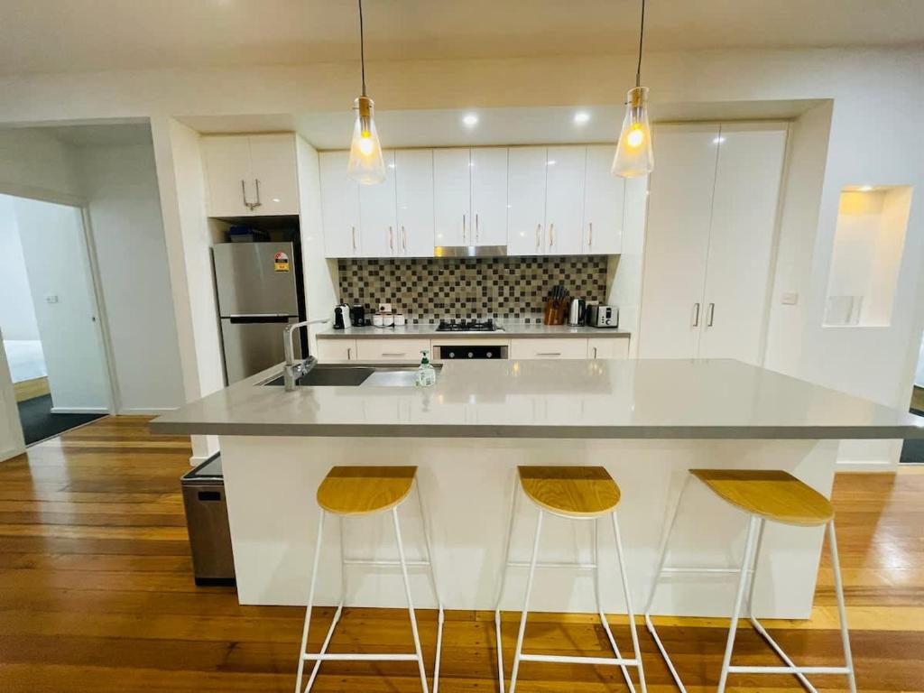 ローズバッドにあるPerfect Family Home pet-friendly in Rosebud plus BBQの白い大きな島(バースツール2つ付)のあるキッチン