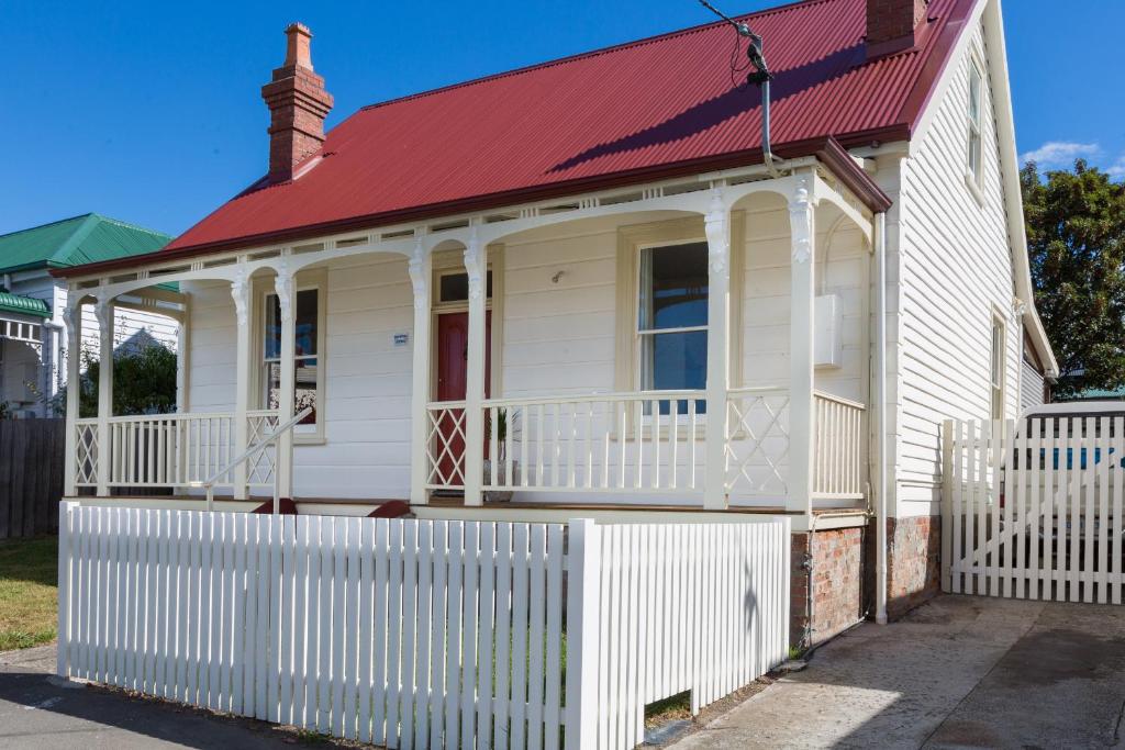 Casa blanca con techo rojo y valla blanca en Brampton Cottage en Hobart