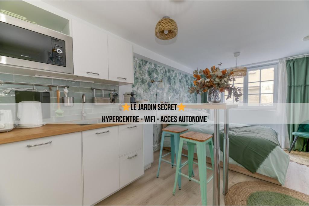 a kitchen with white cabinets and a bed in a room at Le Jardin Secret - Centre ville - WIFI - by CLÉ HÔTES in Saint-Vallier
