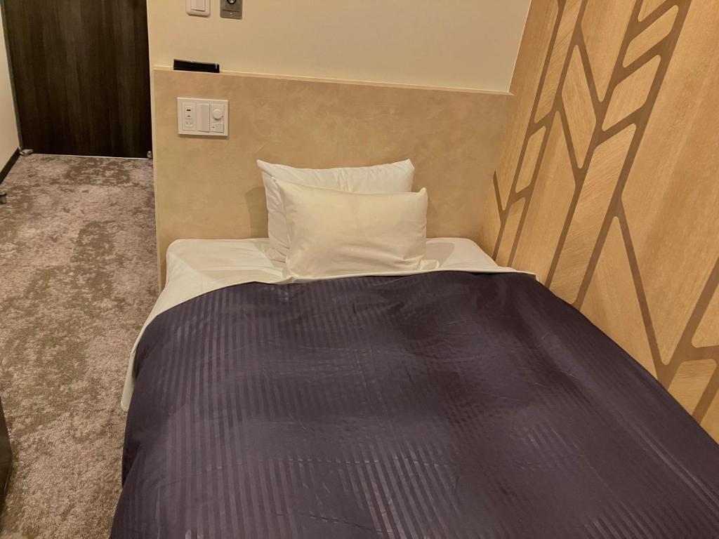 Postel nebo postele na pokoji v ubytování HOTEL LiVEMAX Mihara Ekimae