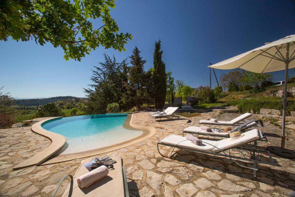 einen Pool mit Liegestühlen und einem Sonnenschirm in der Unterkunft Le Jas de Péguier in Châteauneuf-Val-Saint-Donat