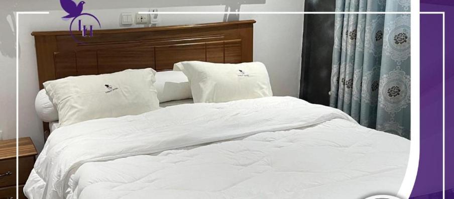 a large white bed with white sheets and pillows at Lively Hotel Makepe in Douala